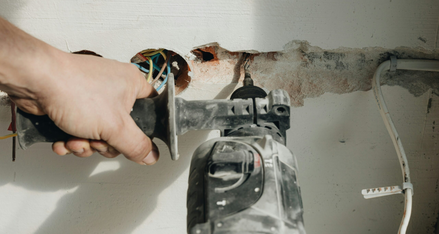 Handwerker verwendet Bohrmaschine für Trockenbauarbeiten an einer Wand